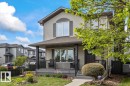Two-story residence featuring light-colored siding, a covered front porch with dark railings, and prominent upper-level windows with dark shutters - 1086 Grantham Drive, Edmonton, AB 