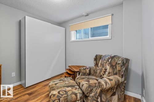 Room featuring a white wall-mounted cabinet, wood-finish flooring, and a window with a roller blind - 1086 Grantham Drive, Edmonton, AB 