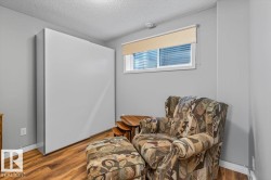Room featuring a white wall-mounted cabinet, wood-finish flooring, and a window with a roller blind - 