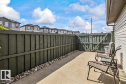 Outdoor patio space featuring a concrete surface, privacy fencing, and a side gate - 