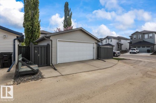 Detached garage with a white overhead door, concrete driveway, and black privacy fencing - 1086 Grantham Drive, Edmonton, AB 