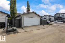Detached garage with a white overhead door, concrete driveway, and black privacy fencing - 