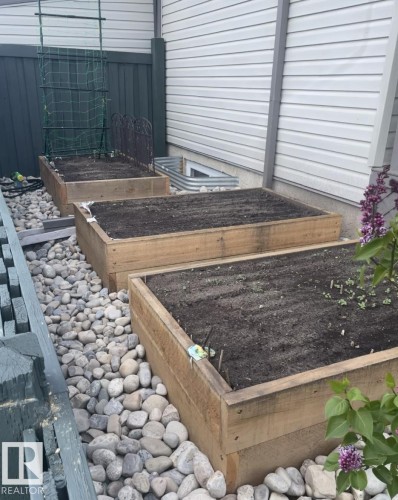 Three raised garden beds with wood-finish frames, set on a river rock base - 1086 Grantham Drive, Edmonton, AB 