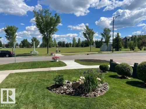 Landscaped front yard featuring a curved sidewalk, a garden bed with river rock and mulch, and manicured shrubs - 1086 Grantham Drive, Edmonton, AB 