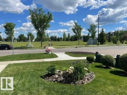 Landscaped front yard featuring a curved sidewalk, a garden bed with river rock and mulch, and manicured shrubs - 