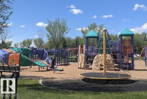 Community playground featuring multiple play structures on a wood chip base - 1086 Grantham Drive, Edmonton, AB 