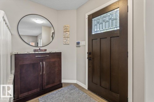 Entryway featuring a dark wood-finish door with leaded glass, tile flooring, and a built-in cabinetry unit with a granite countertop and satin nickel hardware - 1086 Grantham Drive, Edmonton, AB 