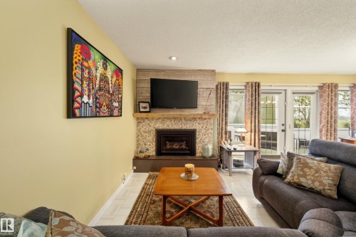 Living area featuring a stone-clad fireplace with wood-finish paneling, a recessed hearth, and a wood mantel - 78 Goodridge Drive, St. Albert, AB 