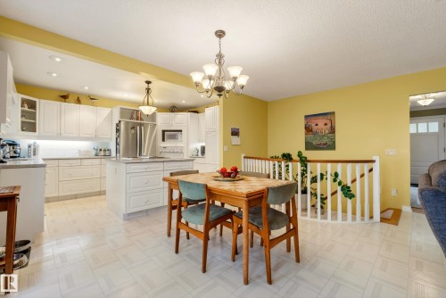 Open-concept kitchen and dining area featuring white cabinetry, stainless steel appliances, recessed lighting, and a center island with additional storage - 78 Goodridge Drive, St. Albert, AB 