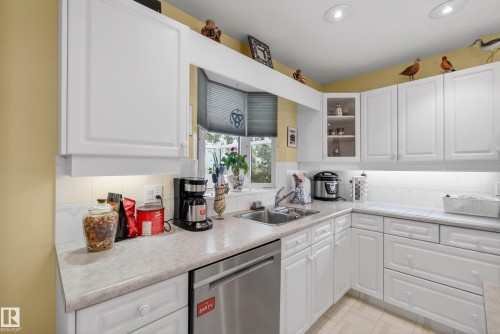 Kitchen featuring white cabinetry, light countertops, a stainless steel dishwasher, and a bay window - 78 Goodridge Drive, St. Albert, AB 