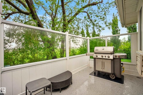 Outdoor patio featuring glass panel railing, composite decking, and a stucco exterior wall - 78 Goodridge Drive, St. Albert, AB 