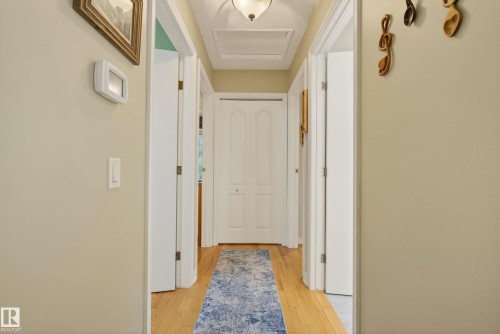 Hallway featuring wood-finish flooring, light-toned walls, and multiple white panel doors - 78 Goodridge Drive, St. Albert, AB 