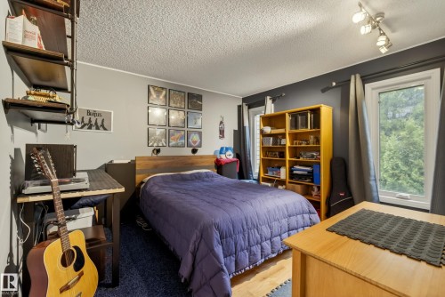 Bedroom featuring wood-finish flooring, two large windows, a textured ceiling, and track lighting - 78 Goodridge Drive, St. Albert, AB 