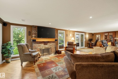 Spacious room featuring a brick-faced fireplace with a wood mantle, hardwood flooring, and recessed lighting - 78 Goodridge Drive, St. Albert, AB 