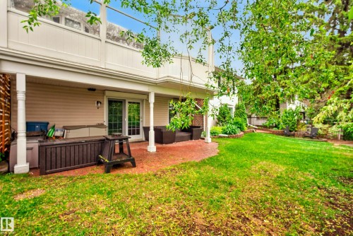 Expansive green lawn with mature trees and a covered patio featuring a sliding glass door - 78 Goodridge Drive, St. Albert, AB 