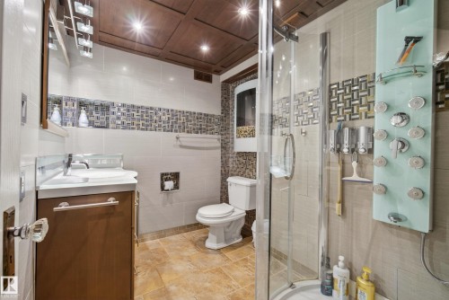 Bathroom featuring a glass-enclosed shower, a wood-finish vanity with a white countertop, a tile accent wall, recessed lighting, and a wood-paneled ceiling - 78 Goodridge Drive, St. Albert, AB 