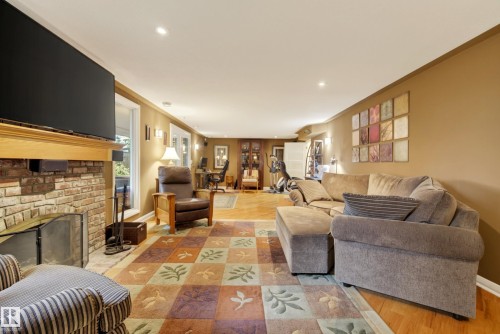 Spacious living area featuring a brick fireplace with a wood mantel, recessed lighting, and hardwood flooring - 78 Goodridge Drive, St. Albert, AB 