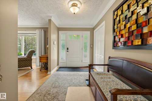 Foyer featuring a white front door with sidelights, a ceiling-mounted light fixture, crown molding, and a closet with bifold doors - 78 Goodridge Drive, St. Albert, AB 