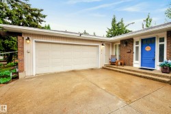 Expansive concrete driveway leading to an attached garage and brick facade entry - 