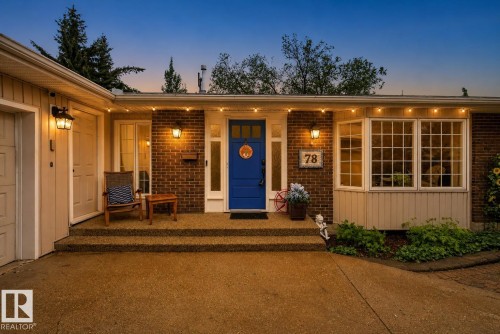 Brick facade with a vibrant blue entry door, an attached garage, a multi-pane bay window, and a concrete driveway - 78 Goodridge Drive, St. Albert, AB 