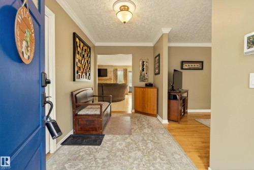 Entryway featuring hardwood flooring, crown molding, a decorative ceiling light fixture, and neutral wall tones - 78 Goodridge Drive, St. Albert, AB 