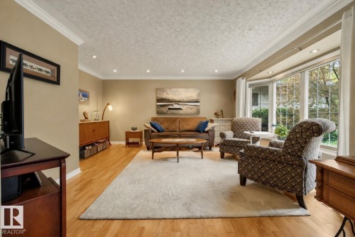Living area featuring wood-finish flooring, recessed lighting, crown molding, a bay window, and neutral wall tones - 78 Goodridge Drive, St. Albert, AB 