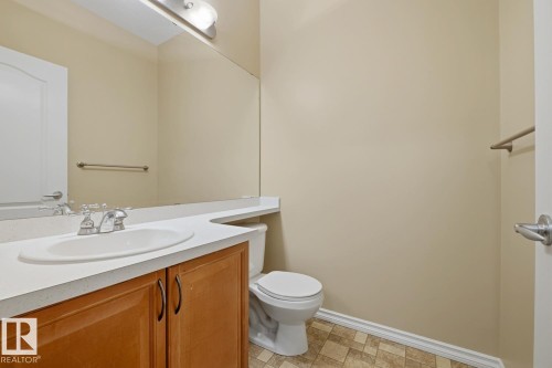 Bathroom featuring a light wood-finish vanity with a white countertop and integrated sink, chrome faucet, and a toilet - 11612 11 Avenue, Edmonton, AB - Indoor Photo Showing Bathroom