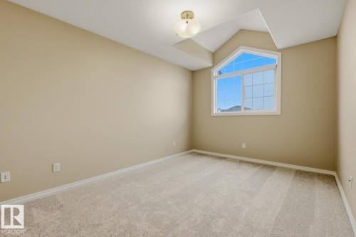 Room featuring a large architectural window, vaulted ceiling accents, neutral wall tones, and plush carpet flooring - 11612 11 Avenue, Edmonton, AB - Indoor Photo Showing Other Room