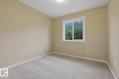 Neutral-toned walls and plush carpeting complement the natural light from the window - 11612 11 Avenue, Edmonton, AB - Indoor Photo Showing Other Room