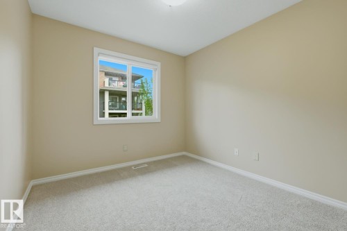 Neutral-toned wall paint with a single window, white trim, and light-colored carpet flooring - 11612 11 Avenue, Edmonton, AB - Indoor Photo Showing Other Room