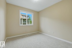 Neutral-toned wall paint with a single window, white trim, and light-colored carpet flooring - 