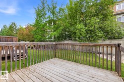 Wood-finish deck with railing overlooking a green lawn, established trees, and a privacy fence - 