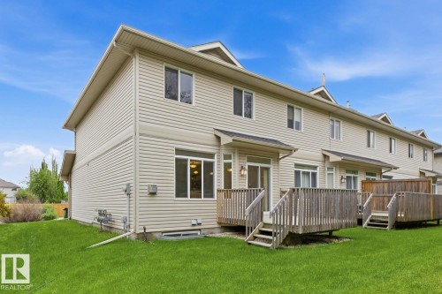 Spacious rear yard with a manicured lawn, an elevated wood deck, and an additional lower-level patio - 11612 11 Avenue, Edmonton, AB - Outdoor