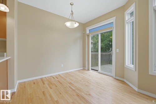 Bright room featuring light wood-finish flooring, a contemporary ceiling fixture, and a sliding glass door providing access to an exterior deck - 11612 11 Avenue, Edmonton, AB - Indoor Photo Showing Other Room