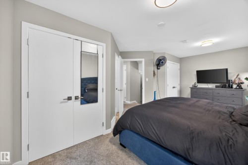 Carpeted room with light gray walls, featuring white bi-fold doors with dark hardware, recessed lighting, and a flush-mount ceiling fixture - 12604 116 Avenue, Edmonton, AB 