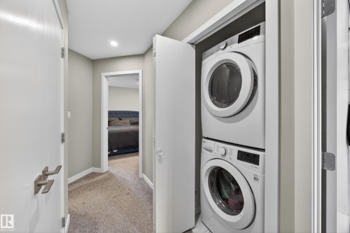 Integrated laundry closet featuring a stacked washer and dryer - 12604 116 Avenue, Edmonton, AB 