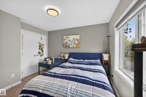 Carpeted room featuring a large window, a flush-mount ceiling light, and white paneled doors - 12604 116 Avenue, Edmonton, AB 