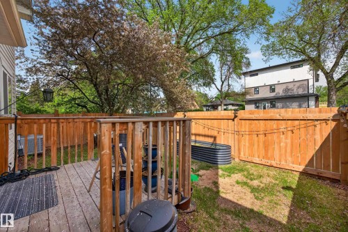 Exterior deck with natural wood railing, leading to a lawn area with a raised garden bed - 12604 116 Avenue, Edmonton, AB 