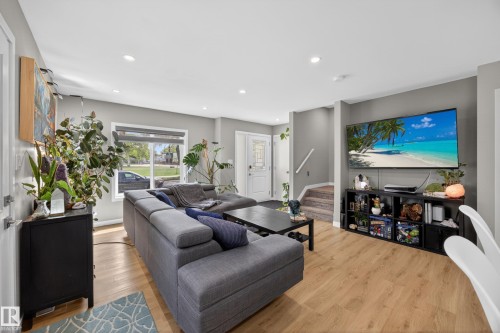 Open-concept living space featuring wood-finish flooring, recessed lighting, and a white front entry door with a decorative glass insert - 12604 116 Avenue, Edmonton, AB 