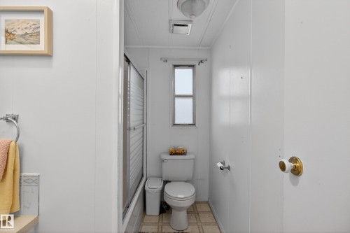 Bathroom featuring a white toilet, frosted window, sliding glass shower enclosure, and tiled flooring - 21 Willowdale Drive, Edmonton, AB - Indoor Photo Showing Bathroom