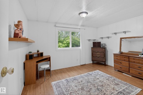 Room featuring wood-finish flooring, white walls, and a single window offering natural light - 21 Willowdale Drive, Edmonton, AB - Indoor