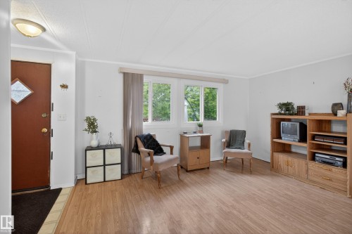 Living area featuring wood-finish flooring, white walls, and a large window with natural light - 21 Willowdale Drive, Edmonton, AB - Indoor