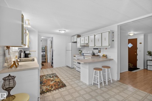 Bright kitchen featuring white cabinetry, light countertops, and neutral flooring - 21 Willowdale Drive, Edmonton, AB - Indoor Photo Showing Kitchen
