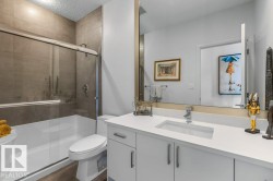Main Floor 4 Piece Bathroom featuring Quartz Counters, White Cabinets, and Tiled Shower - 