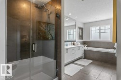 Primary Ensuite featuring Separate Glass and Tile Shower, Jacuzzi Bathtub, White Cabinets and Quartz Counters, and Separate Water Closet - 