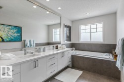 Primary Ensuite featuring Separate Glass and Tile Shower, Jacuzzi Bathtub, White Cabinets and Quartz Counters, and Separate Water Closet - 