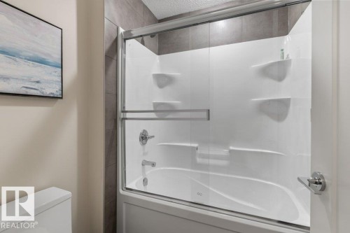 Bathroom featuring a Double Vanity with White Cabinetry, Quartz Counters, and Bathtub with Wall Surround Kit - 4476 Suzanna Crescent, Edmonton, AB - Indoor Photo Showing Bathroom