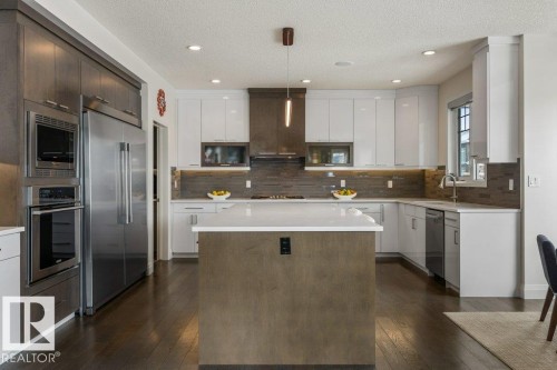 Kitchen Features Dark Hardwood Flooring, Two Tone Kitchen Cabinets, Gas Stove, Wall Oven, and White Quartz Counters - 4476 Suzanna Crescent, Edmonton, AB - Indoor Photo Showing Kitchen With Upgraded Kitchen