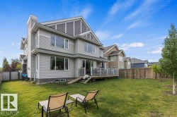Summer View of the Back Exterior of the home featuring Deck,  and fenced yard space - 