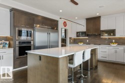 Kitchen Features Dark Hardwood Flooring, Two Tone Kitchen Cabinets, Gas Stove, Wall Oven, and White Quartz Counters - 